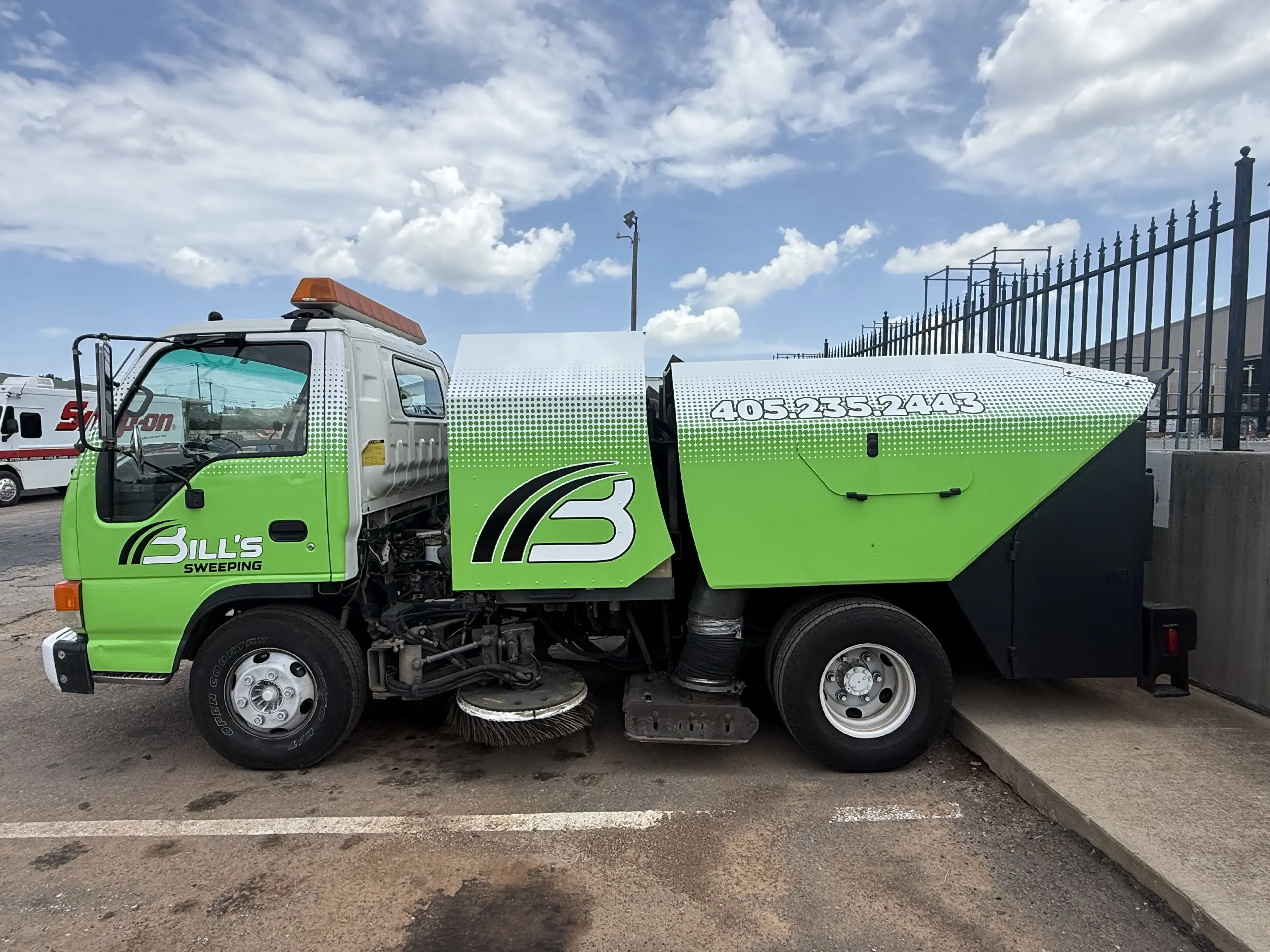 Bill's Pavement sweeping truck cleaning a commercial parking lot